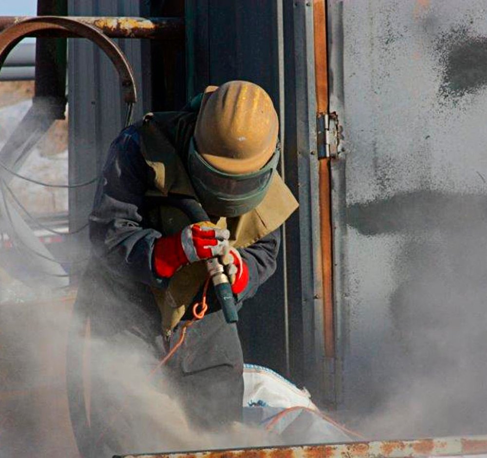 Trabajador utilizando equipo de sand blast para aplicar arena silica para sand blast